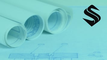 Rolled architectural blueprints representing the operational planning required to align marketing, sales, and business growth Selkire