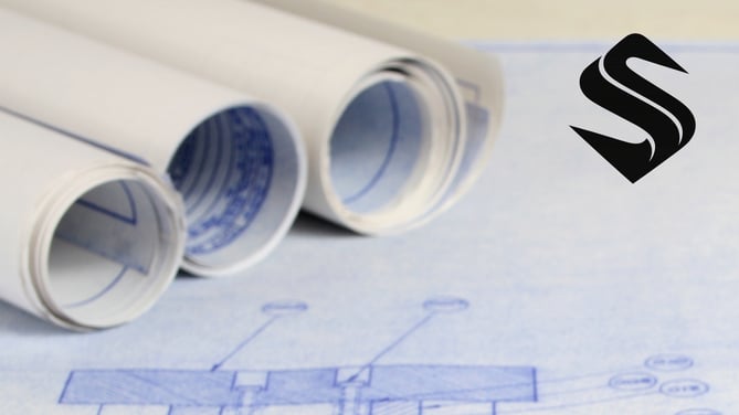 Rolled architectural blueprints representing the operational planning required to align marketing, sales, and business growth Selkire